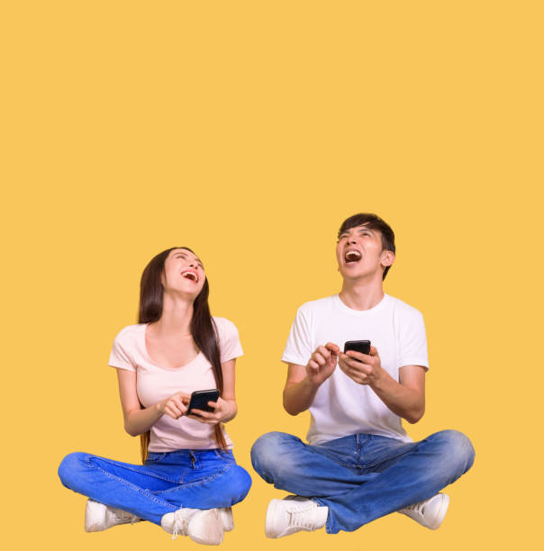 Excited young couple using mobile phone and looking above stock photo