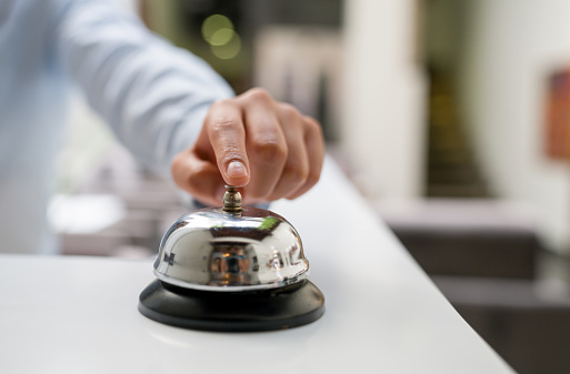 Close-up on a receptionist and ringing the bell at a hotel - hospitality industry concepts