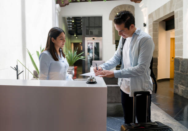 istock Tourist doing the check-in at a hotel and signing a document 1346447891