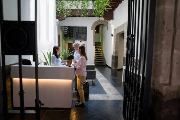 Happy Latin American couple of travelers doing the check-in at the hotel's reception - people traveling concepts