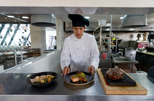 Mexican chef cooking in the kitchen of a restaurant and serving plates - food and drink cocnepts