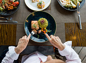 Close-up on a woman eating salmon for dinner at a restaurant