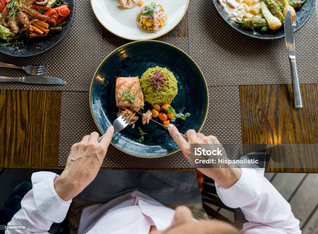 Close-up on a woman eating salmon for dinner at a restaurant Close-up on a woman eating salmon for dinner at a restaurant - food and drink concepts Eating Stock Photo
