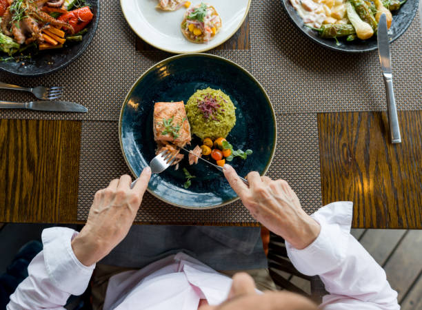 close-up on a woman eating salmon for dinner at a restaurant - eating eat silverware horizontal imagens e fotografias de stock