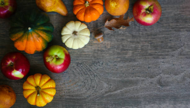 istock Fall Vegetables and Fruit with Pumpkins, Acorn Squash, Apples, Pears and Oak Leaves Over Dark Wood Table 1346454575