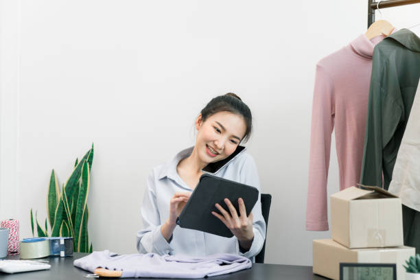 istock Asian entrepreneur talking on the phone with a customer while checking inventory on a tablet. 1346462565