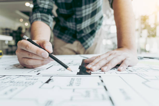 istock Interior designer or architect reviewing blueprints and holding pencil drawing on desk at home office. 1346462590