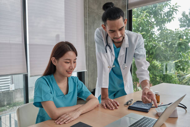 Two uniformed young doctors work in medical clinic office.