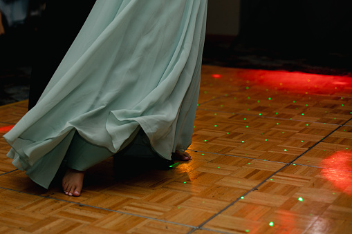 Close up of dancing woman - bare foot, flowy dress with party lights.