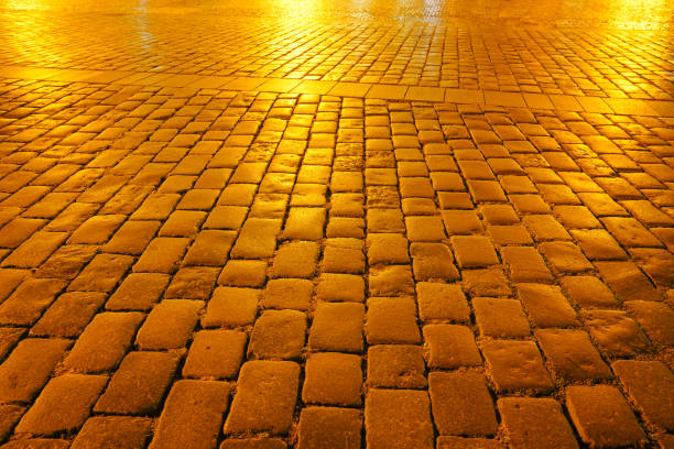 Golden hue at night on empty cobbled street pattern as background image.