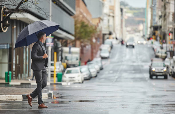 ujęcie przystojnego biznesmena idącego do pracy w deszczowy dzień - cold rain parasol gray zdjęcia i obrazy z banku zdjęć