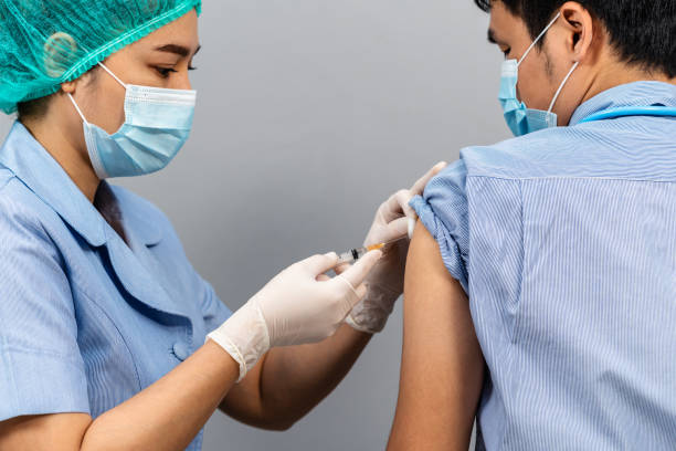 istock Nurse or Medical professionals holding syringe and using cotton before make injection to dortor in mask. Covid-19 or coronavirus vaccine 1346476908