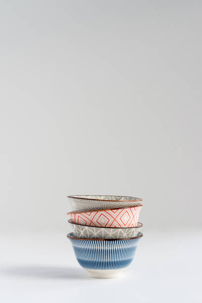 Blue, gray and red small ceramic empty bowls stacked on white background