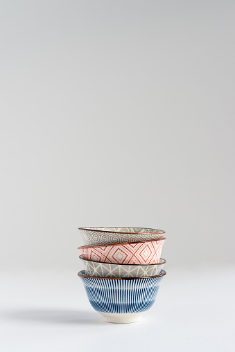 Blue, gray and red small ceramic empty bowls stacked on white background