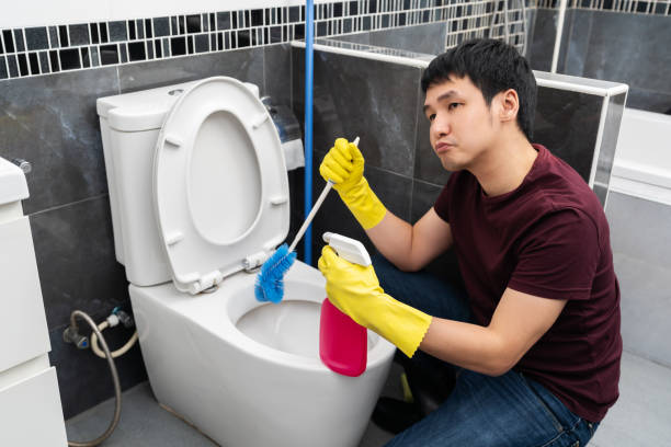 istock bored man cleaning toilet bowl in bathroom 1346477077