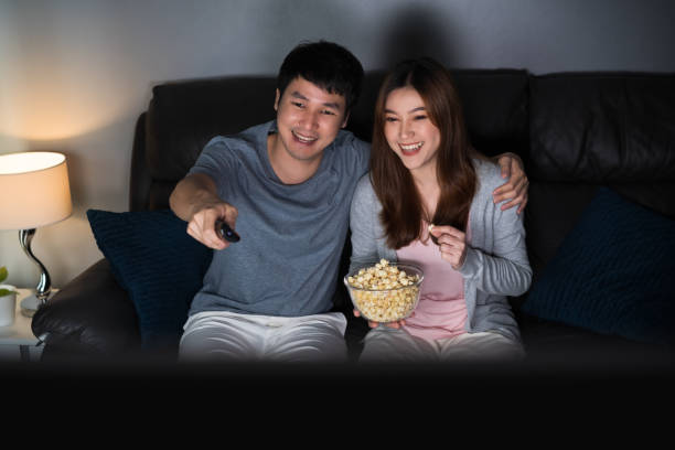 istock happy couple watching TV on sofa at night 1346477107
