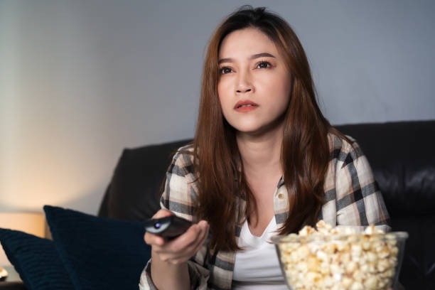 istock woman watching TV on sofa at night 1346477154