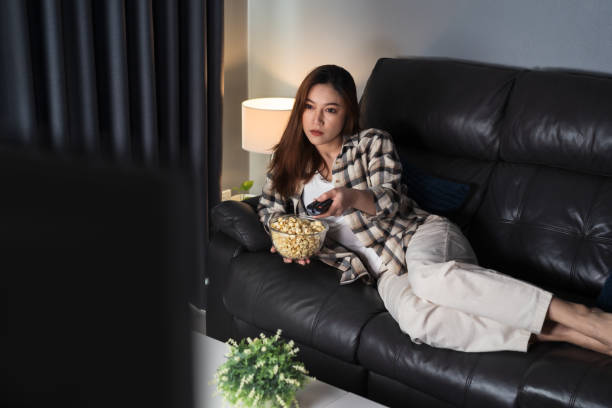 istock woman watching TV on sofa at night 1346477156
