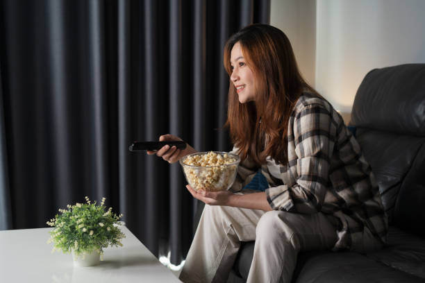 istock happy woman watching TV on sofa at night 1346477159