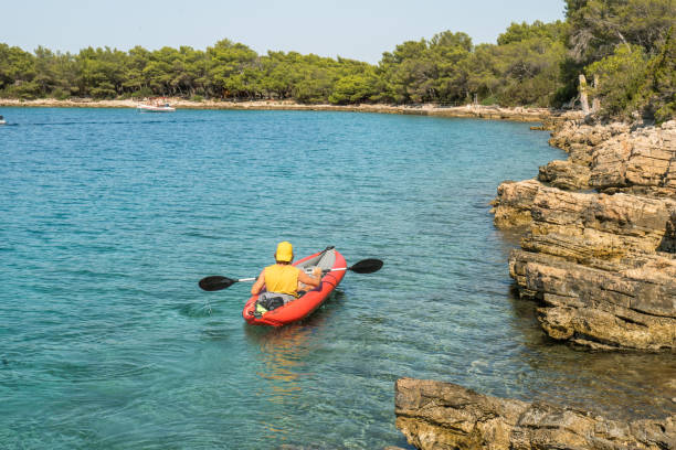 istock Young man canoeing on calm sea in summer 1346482510