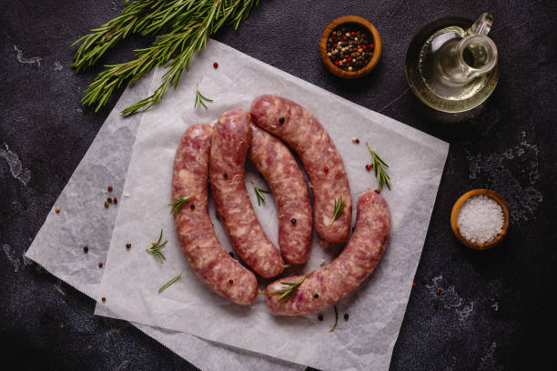 istock Raw sausages and ingredients for cooking on a black stone table 1346484832