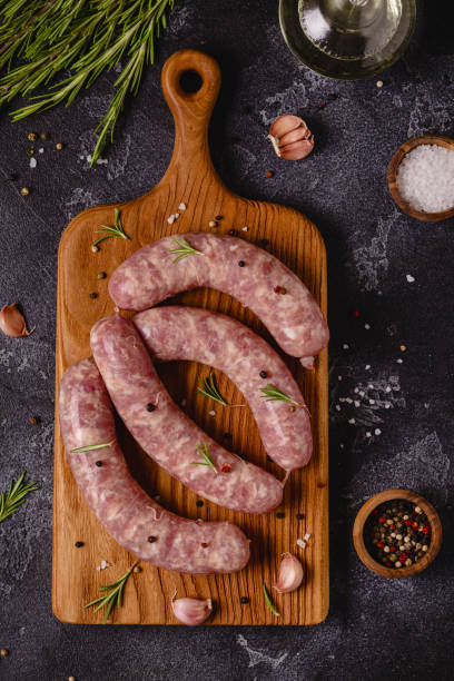 istock Raw sausages and ingredients for cooking on a black stone table 1346485395