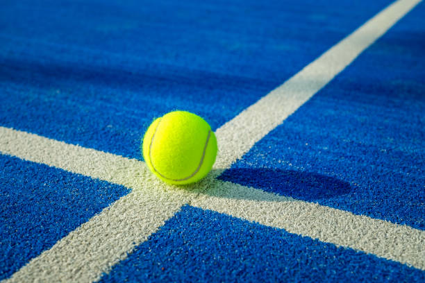 żółta piłka tenisowa w korcie na niebieskiej trawie - wiosłowa piłka tenisowa na korcie na niebieskiej murawie - tennis court tennis ball racket zdjęcia i obrazy z banku zdjęć