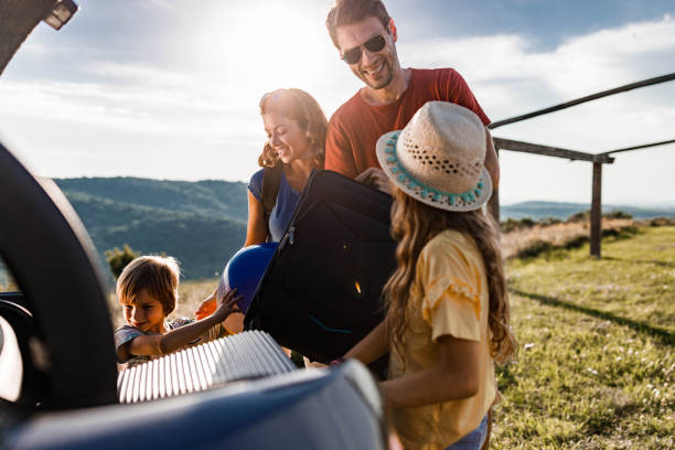 istock Happy family talking while packing their luggage into a car trunk. 1346489961