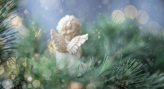 vista trasera del ángel rezando sobre el fondo del árbol de Navidad y luces doradas photo