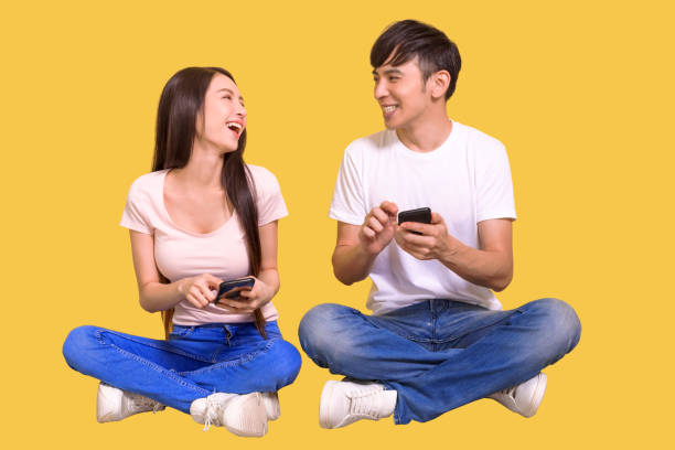 istock Happy young  couple sitting on floor and using smart phone 1346491100