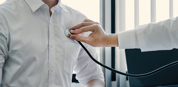 The doctor used a stethoscope to listen to the heartbeat of the man patient, medical checkup concept.