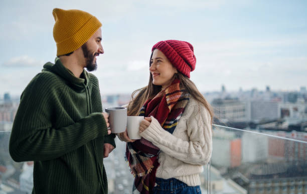 giovane coppia con caffè in piedi e guardandosi l'un l'altro all'aperto sul balcone con vista urbana. - balcony house golf home interior foto e immagini stock