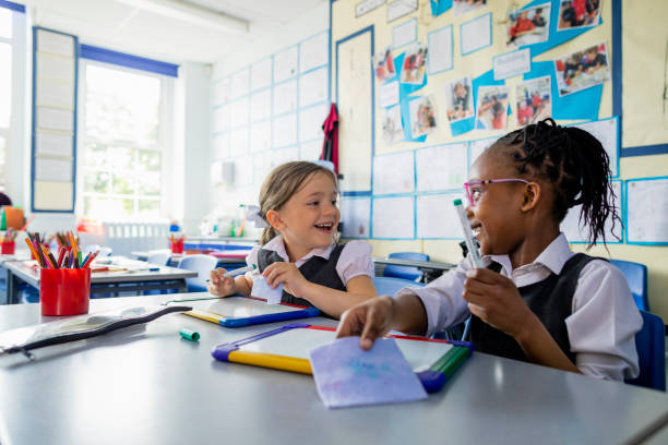 Girls having Fun at School Primary school students sitting in a classroom writing on a mini whiteboards in the North East of England. The girls are laughing together. braided hair photos stock pictures, royalty-free photos & images