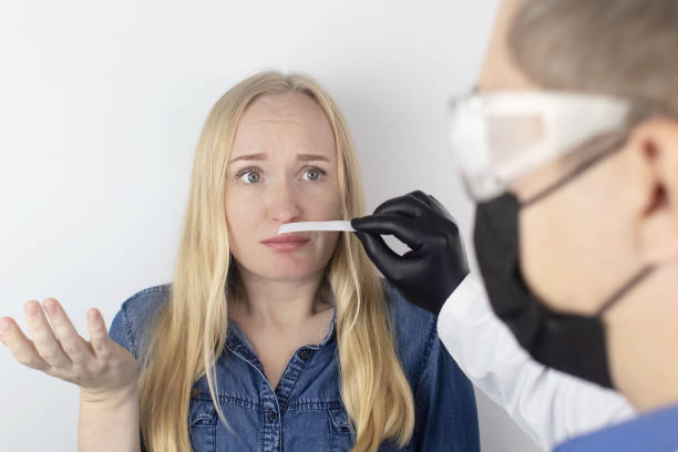 The girl complains to the doctor about the loss of smell. The doctor conducts a sense of smell test. Diagnostics of covid-19. Symptoms of the coronavirus. Quarantine and isolation. Test for sars-cov-2 stock photo