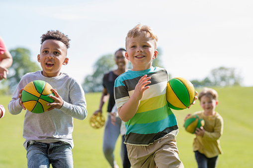Children playing sports games while at preschool during active time in the North East of England. They are running while carrying balls.