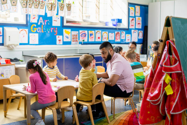 Learning about Creativity Primary school students sitting in an art classroom being taught by a teacher in the North East of England. preschool classroom jobs stock pictures, royalty-free photos & images