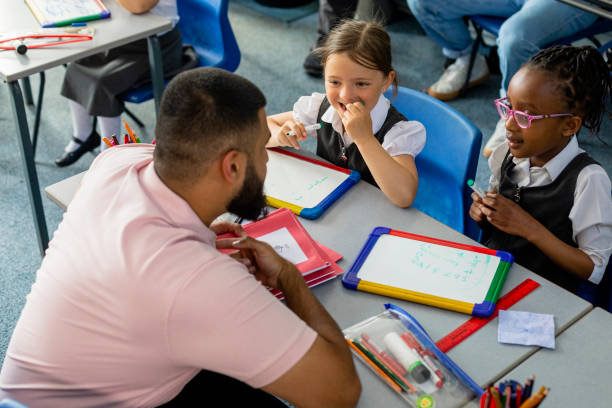 Making Learning Fun Primary school students sitting in a classroom being taught by a teacher in the North East of England. The pupils are learning on mini whiteboards. math teacher stock pictures, royalty-free photos & images