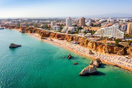 Aerial view of touristic Portimao with wide sandy Rocha beach full of people, Algarve, Portugal