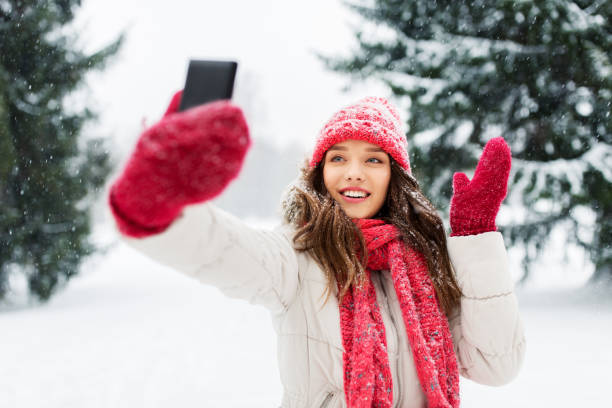 young woman taking selfie by smartphone in winter