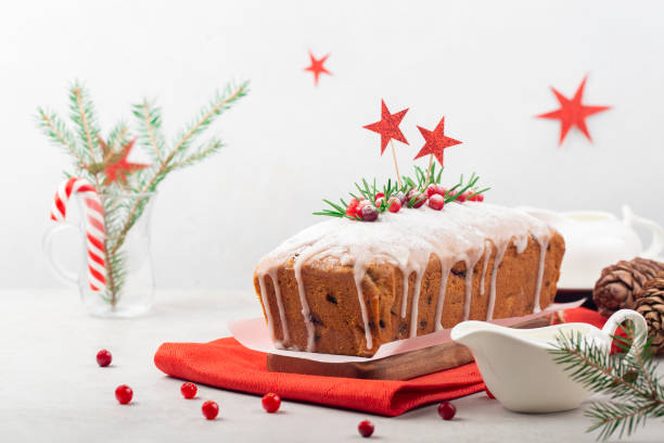 Christmas celebration:  fruit cake with cranberries Christmas celebration:  fruit cake with cranberries, raisins and almonds, decorated with fresh cranberries and rosemary. Christmas decoration, white background. Close up. Copy space. fruitcake stock pictures, royalty-free photos & images