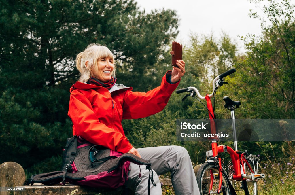 Cycle ride through a forest Mature woman on her mobile phone relaxing during a cycle cycling in the Culbin Forest in the Morayshire district of Scotland. Cycling Stock Photo