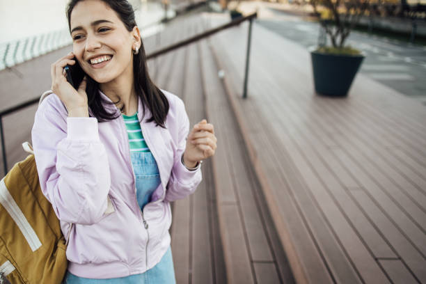 istock Happy student walking by the river and chatting on mobile phone 1346516751