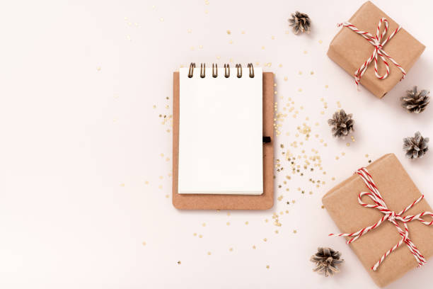 istock Notebook blank paper mockup, golden stars confetti, gift boxes on beige background 1346517636