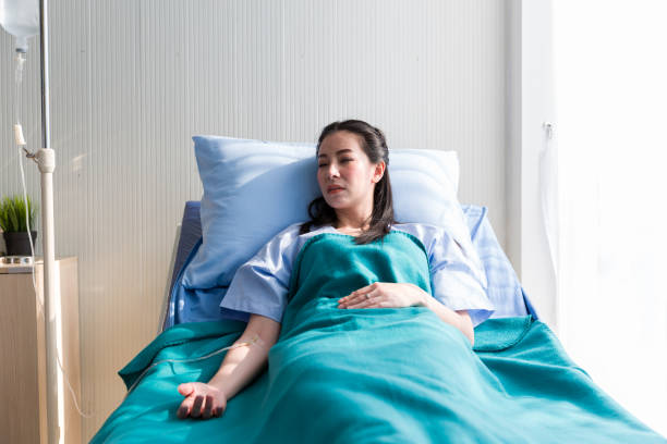 la paciente acostada le da agua salada en la cama del hospital y su mano con aguja intravenosa de goteo médico. concepto salino de los pacientes. - intravenous infusion fotografías e imágenes de stock