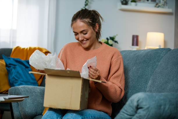 istock Cheerful young woman opening a package she got delivered 1346519034