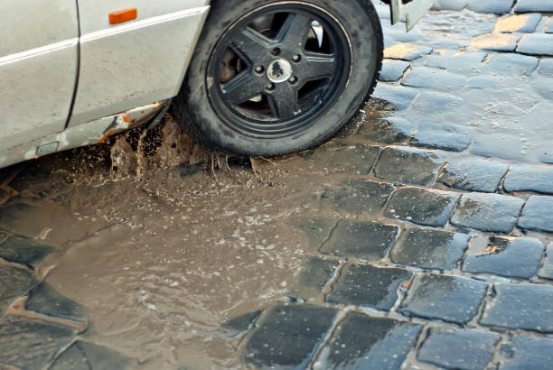 istock Water splashes from a car wheel. Dirty cobblestones with puddles. Early spring and snowfall. Blur as an artistic effect to convey movement. 1346522830