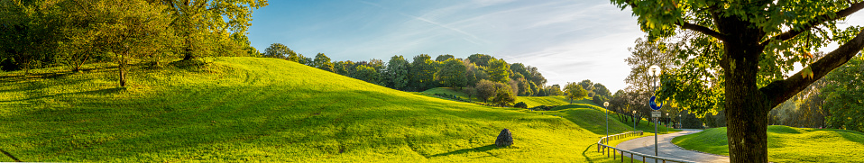 Large panorama of the Olympia Park in Munich in a fall tranquil afternoon when the sunlight bathes the grass