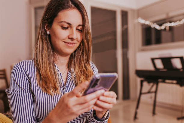 istock Smiling woman using cellphone during christmas celebration at home 1346525758