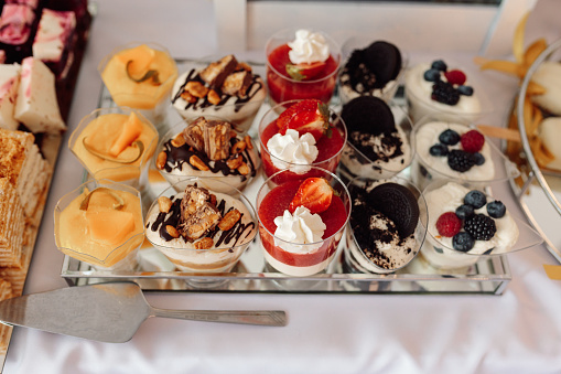 Several varieties of cakes in baskets on plates, decorated with butter cream or curd cream with fruits and berries, top view, concept of food in holiday.