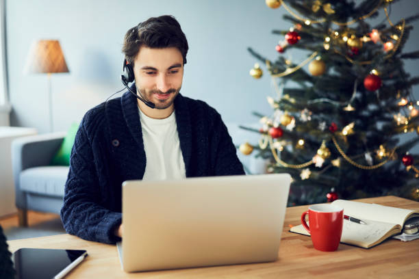 Young adult man with headset working from home during Christmas holidays stock photo